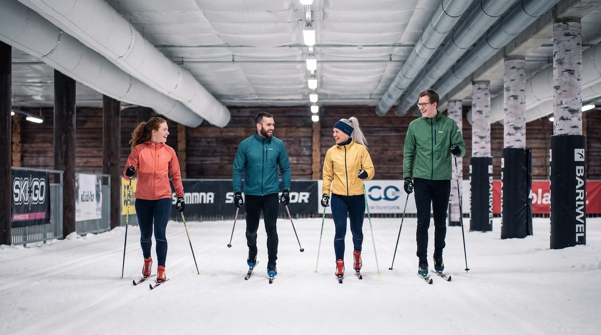 Fyra vänner åker längdskidor tillsammans i inomhusskidhallen Skidome på Kviberg Park.